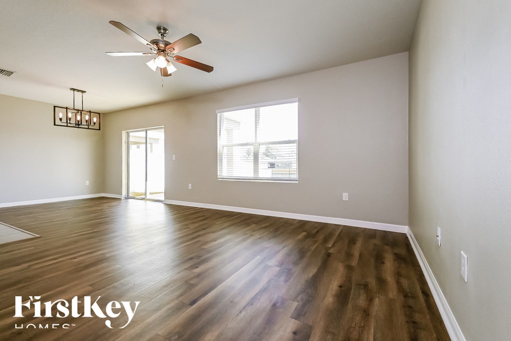 an empty living room with hardwood floors and a ceiling fan