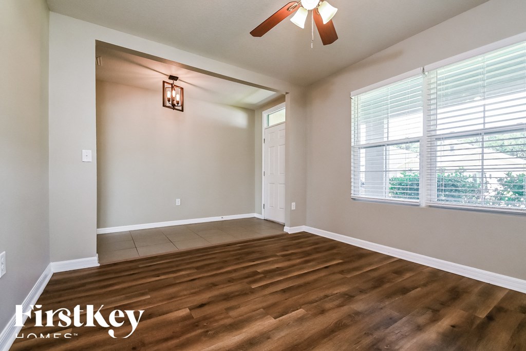 an empty living room with wood flooring and a ceiling fan