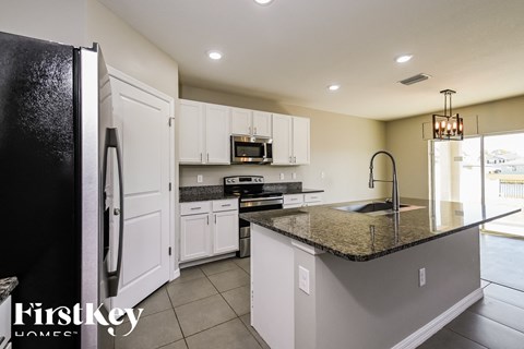 a kitchen with white cabinets and granite counter tops