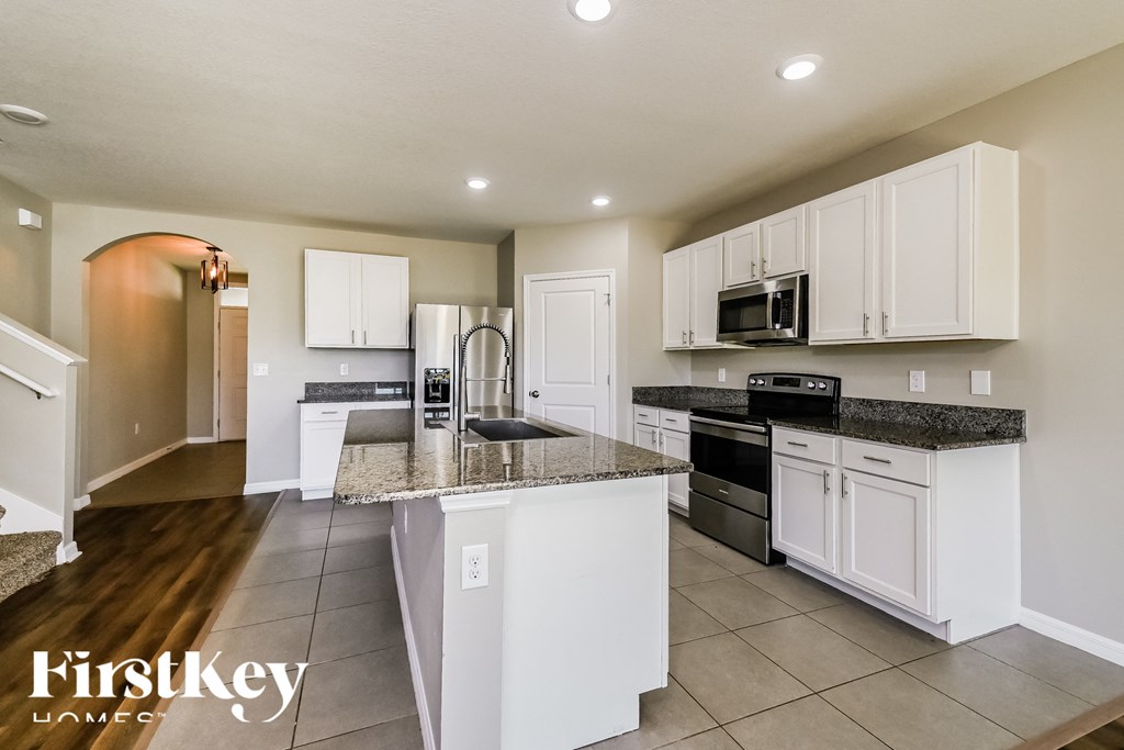 a large kitchen with white cabinets and granite counter tops