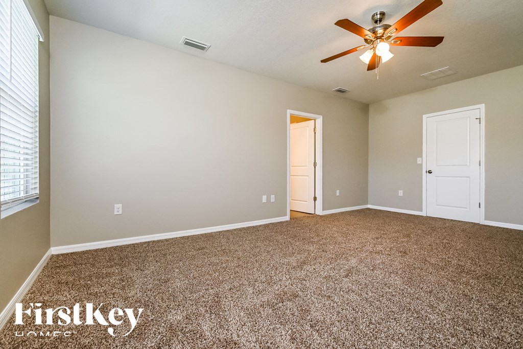 the master bedroom has a carpeted floor and a ceiling fan