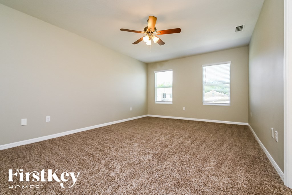 the master bedroom has a carpeted floor and a ceiling fan