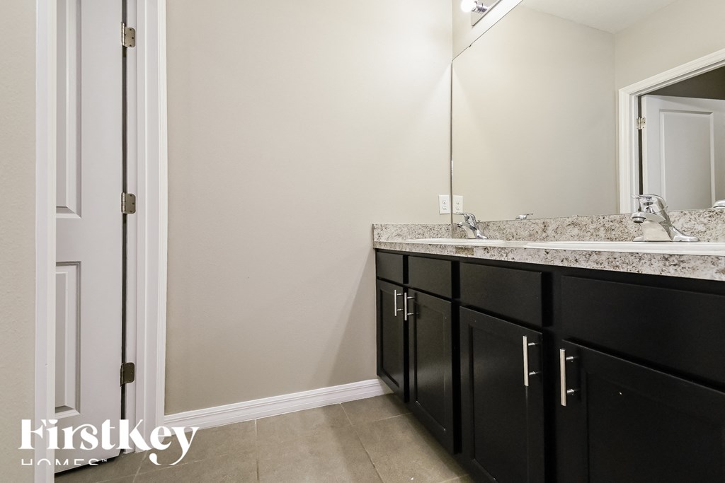 a bathroom with black cabinets and a sink and a mirror
