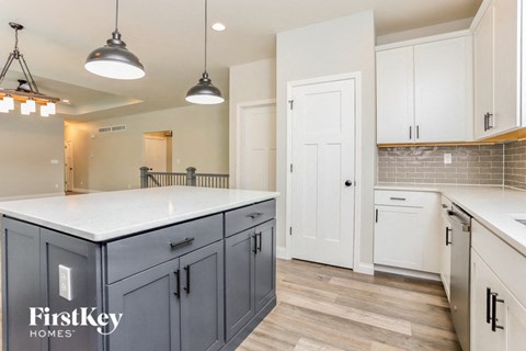 A kitchen with a white counter top and dark grey cabinets.