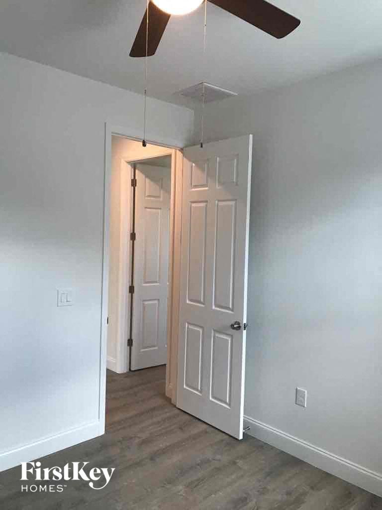 an empty room with a white door and a ceiling fan