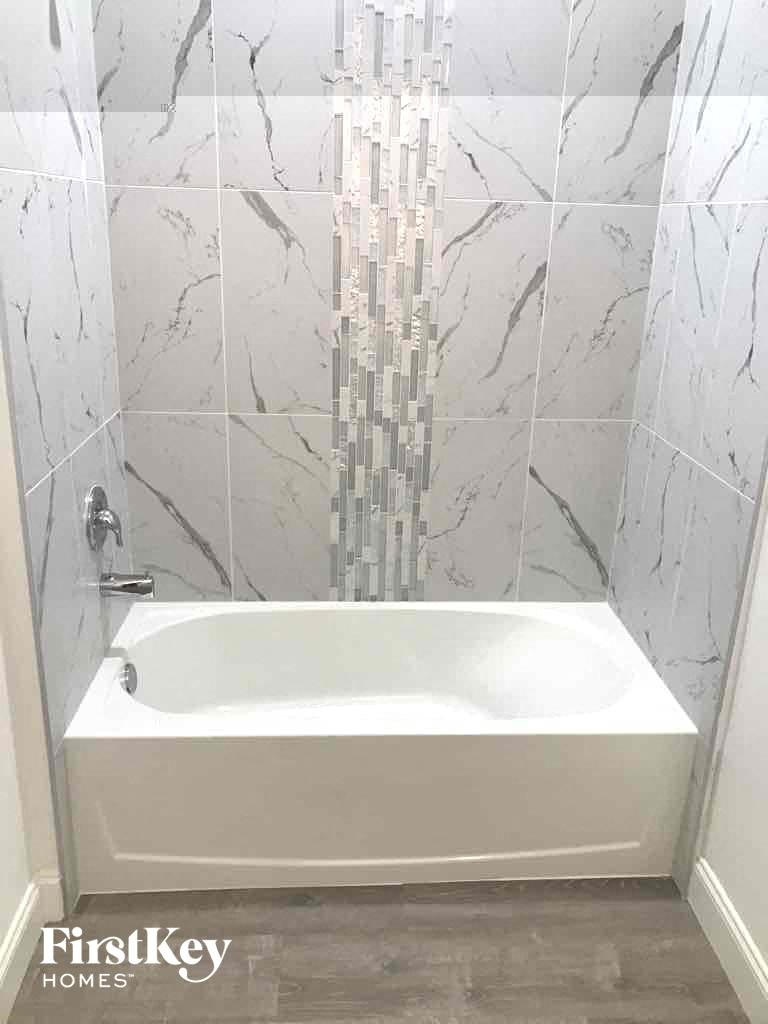 a large white tub in a white tiled bathroom