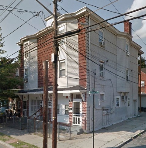A two-story house with a red brick chimney and a white facade.
