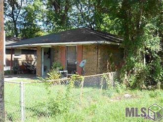 a small brick house with a fence in front of it