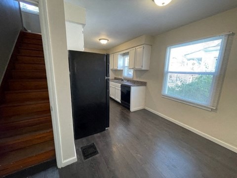 a small kitchen with a black refrigerator and a staircase