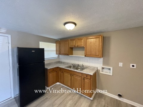 A kitchen with wooden cabinets and a black fridge.