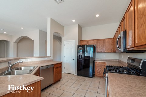A kitchen with wooden cabinets and a black refrigerator.