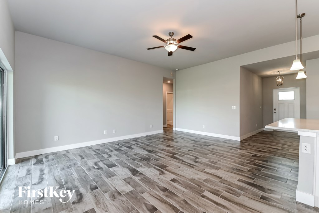 A spacious room with a wood floor and a ceiling fan.