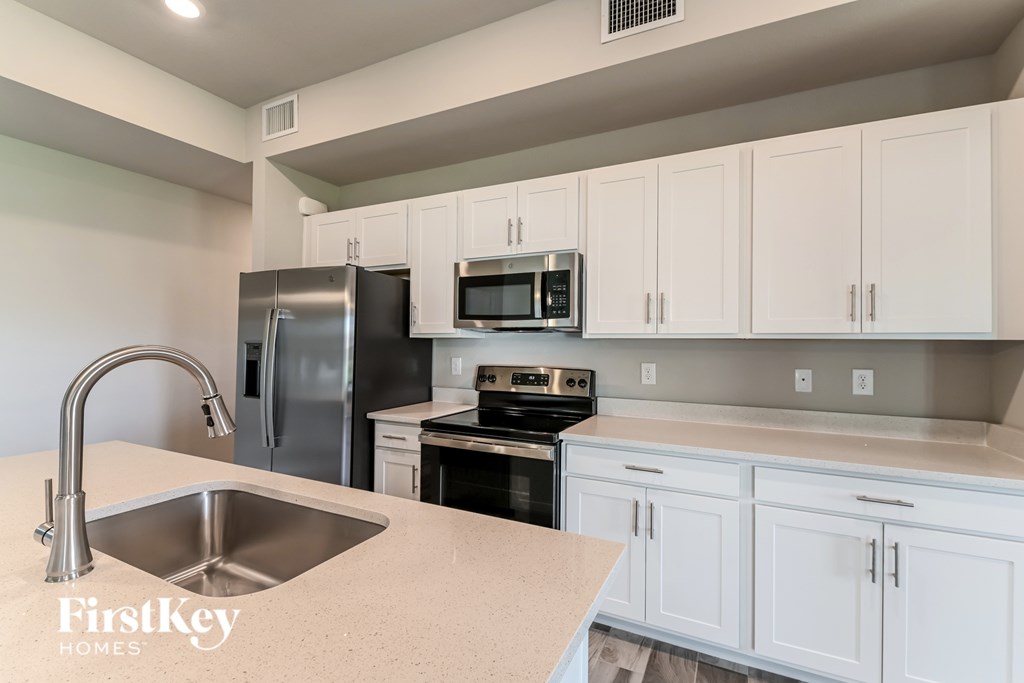 A kitchen with a stainless steel refrigerator and a stainless steel sink.