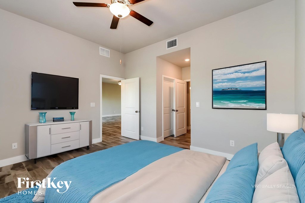 A bedroom with a bed, a television, and a painting of a beach scene.