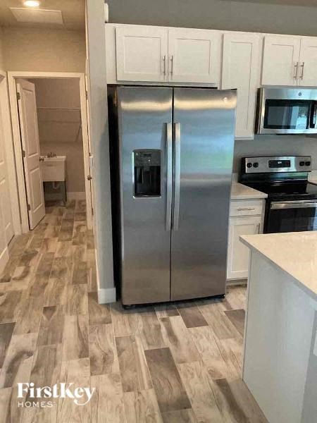 A kitchen with a stainless steel refrigerator and wooden flooring.