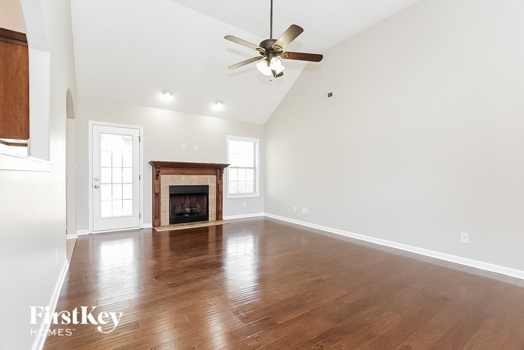 an empty living room with a fireplace and a ceiling fan