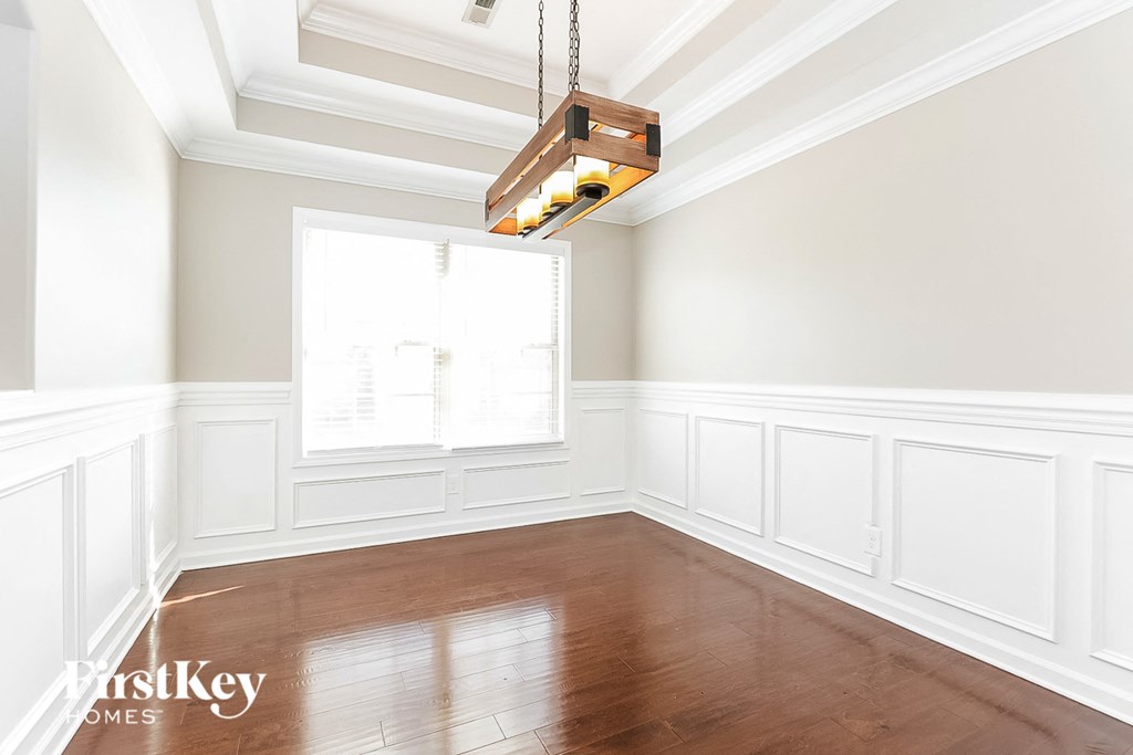 an empty room with white walls and wood floors and a chandelier