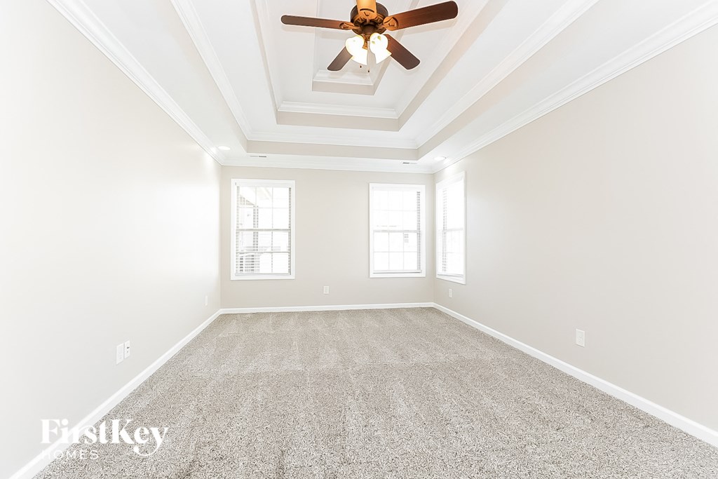 an empty living room with a ceiling fan and carpet