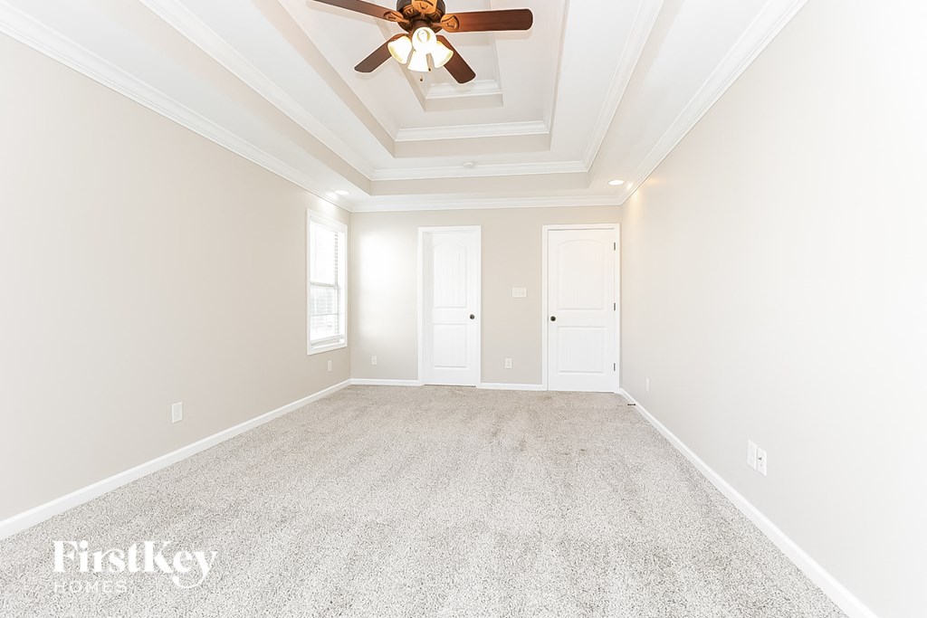 a empty living room with a ceiling fan and a carpeted floor