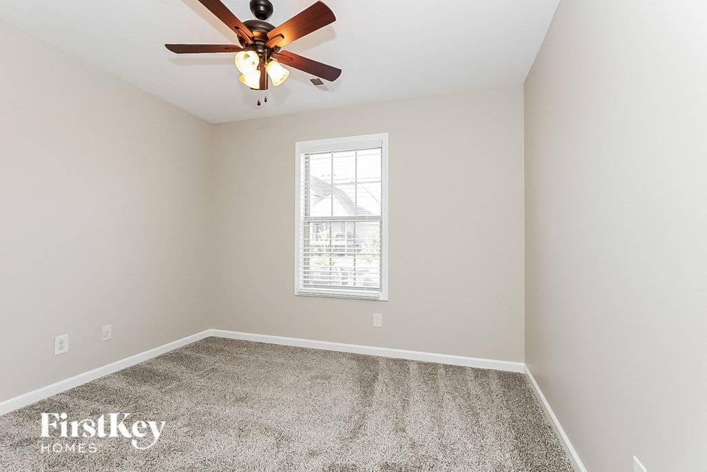 a bedroom with a ceiling fan and a carpet