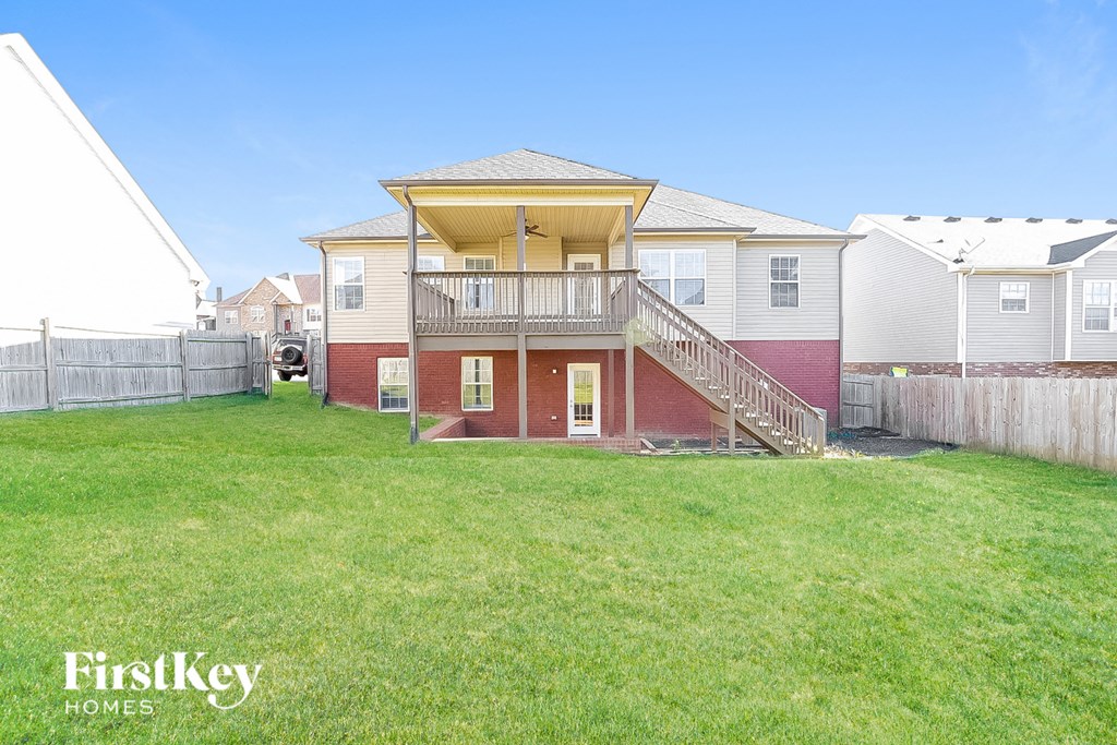 a backyard with a house with a deck and a grass yard
