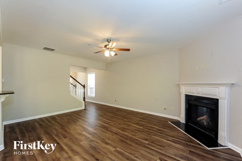 A spacious living room with a fireplace and a ceiling fan.