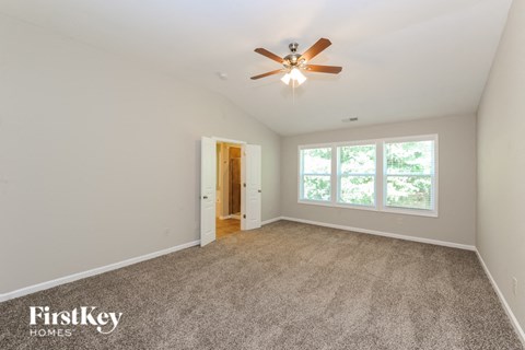 A room with a ceiling fan and carpeted floor.