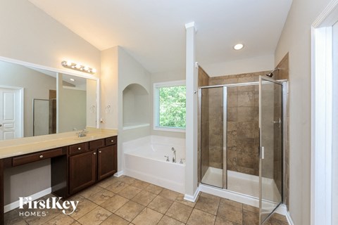 A large, empty bathroom with a walk-in shower and a bathtub.