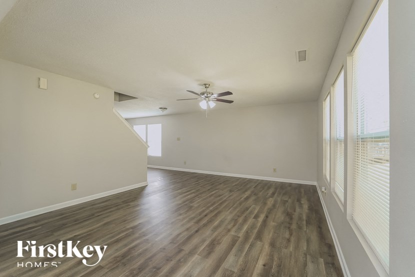 an empty living room with wood floors and a ceiling fan