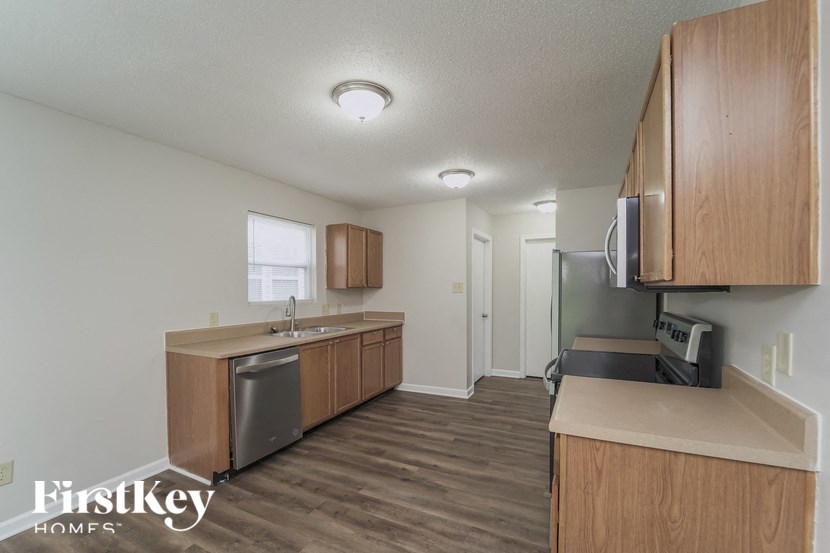 an empty kitchen with wood flooring and wooden cabinets