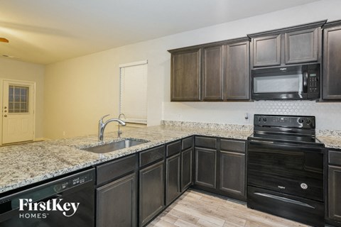 A kitchen with black cabinets and a FirstKey Homes sign.