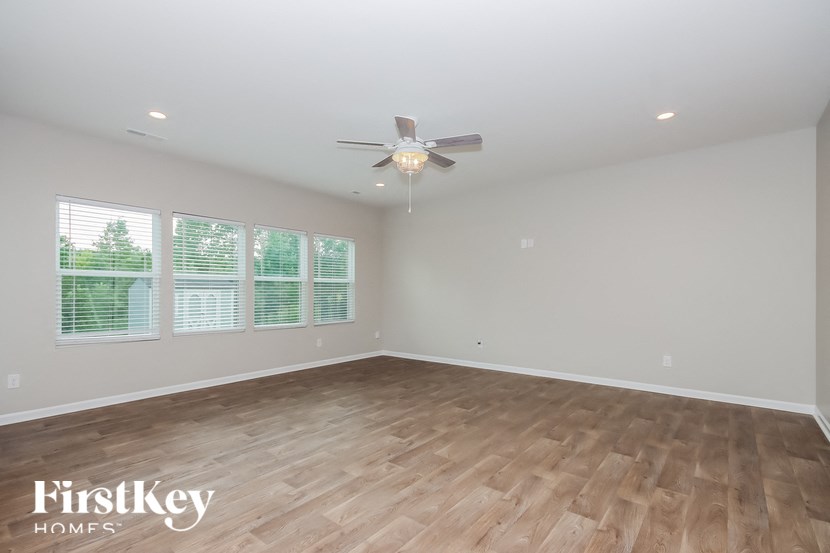 the spacious living room with wood flooring and a ceiling fan