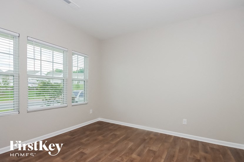 the spacious living room with wood flooring and three windows