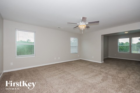 a living room with carpet and a ceiling fan