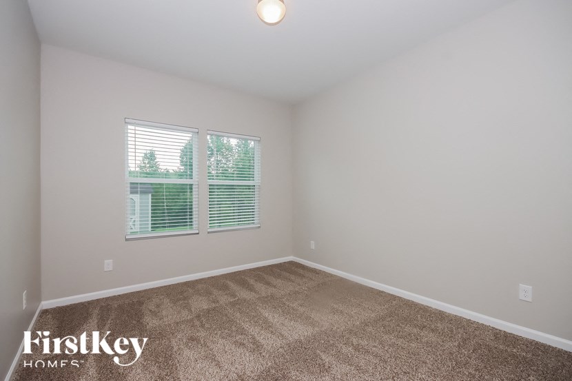 the second bedroom with carpeted flooring and a window