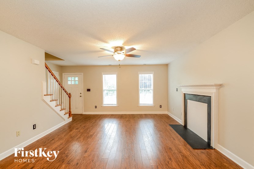 an empty living room with a ceiling fan and a fireplace