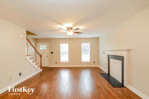 an empty living room with a ceiling fan and a fireplace