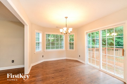 an empty dining room with wood flooring and large windows