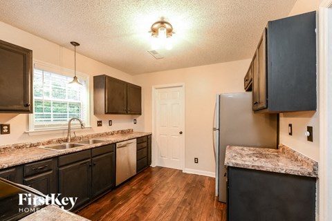 the kitchen of a home with black cabinets and a stainless steel refrigerator