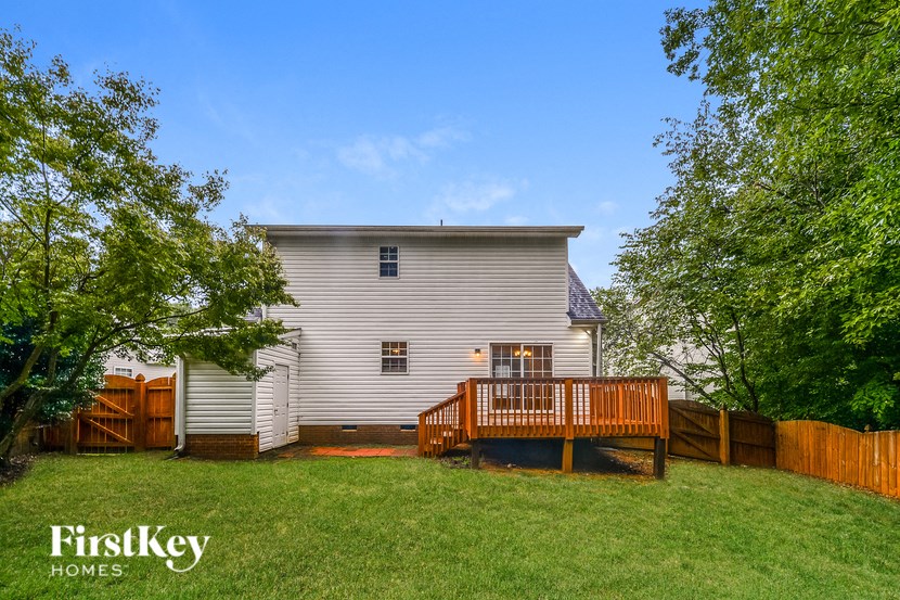 a backyard with a deck and a white house