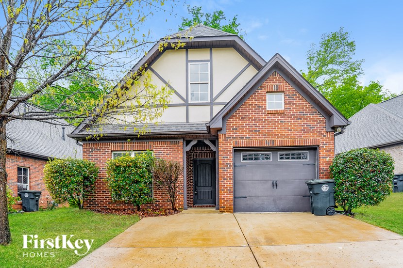 A brick house with a black garage door is for sale.