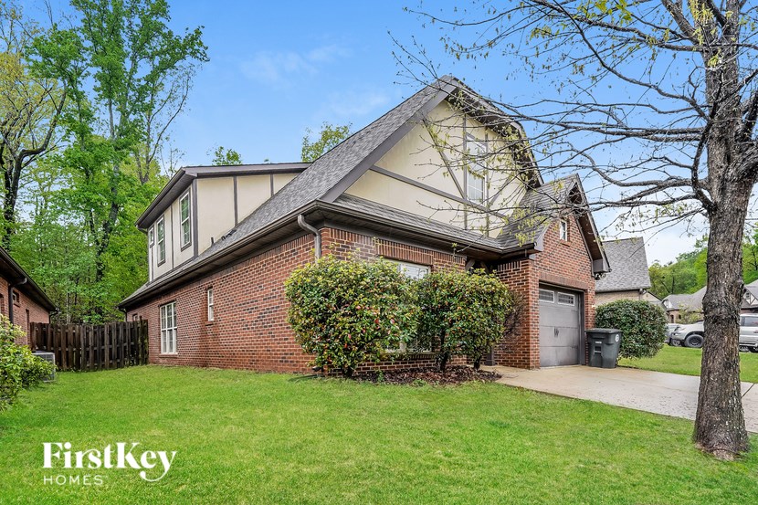 A house with a well-kept lawn and a tree in front.
