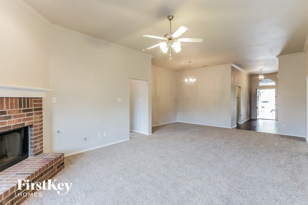 A spacious living room with a fireplace and a ceiling fan.