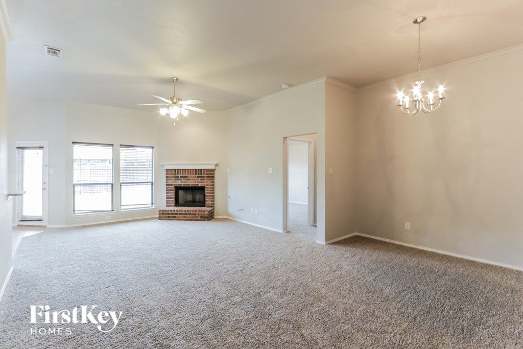 A spacious living room with a fireplace and a chandelier.