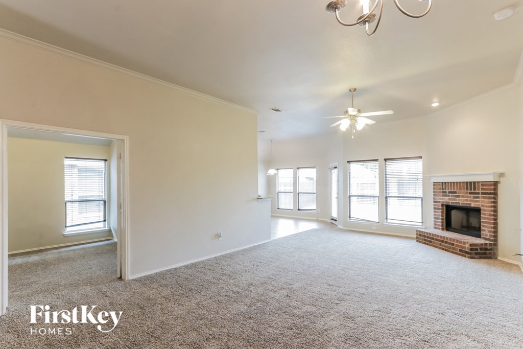 A spacious living room with a fireplace and a chandelier.