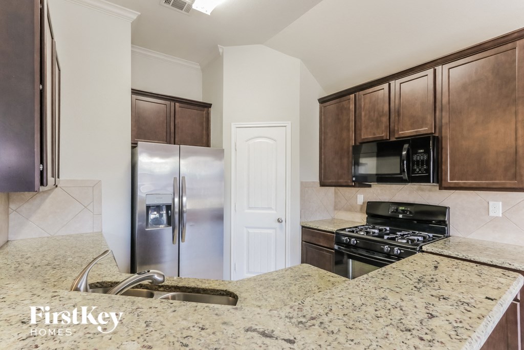A kitchen with granite countertops and a stainless steel refrigerator.
