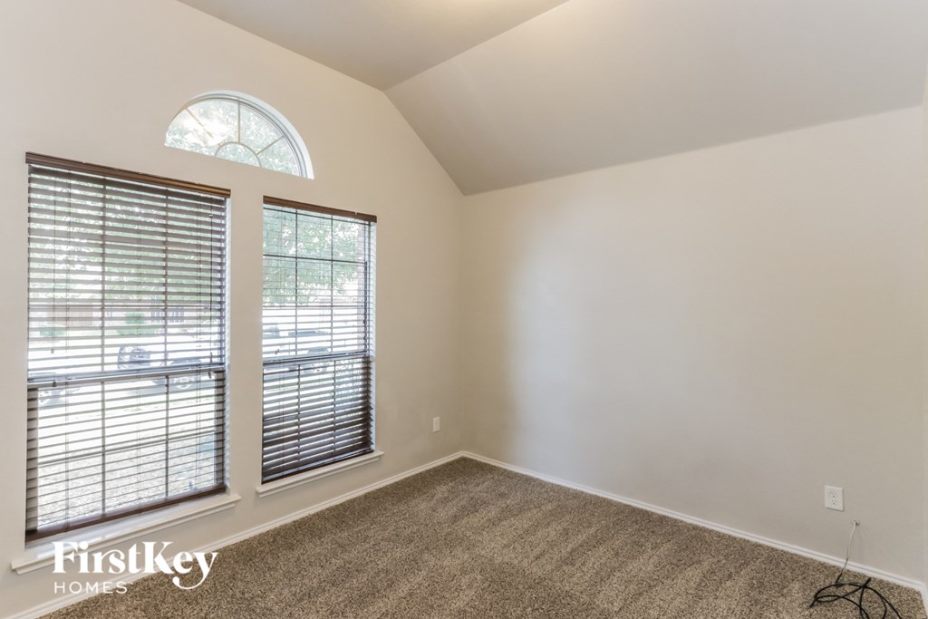 A room with a carpeted floor, a window with blinds, and a FirstKey Homes logo.