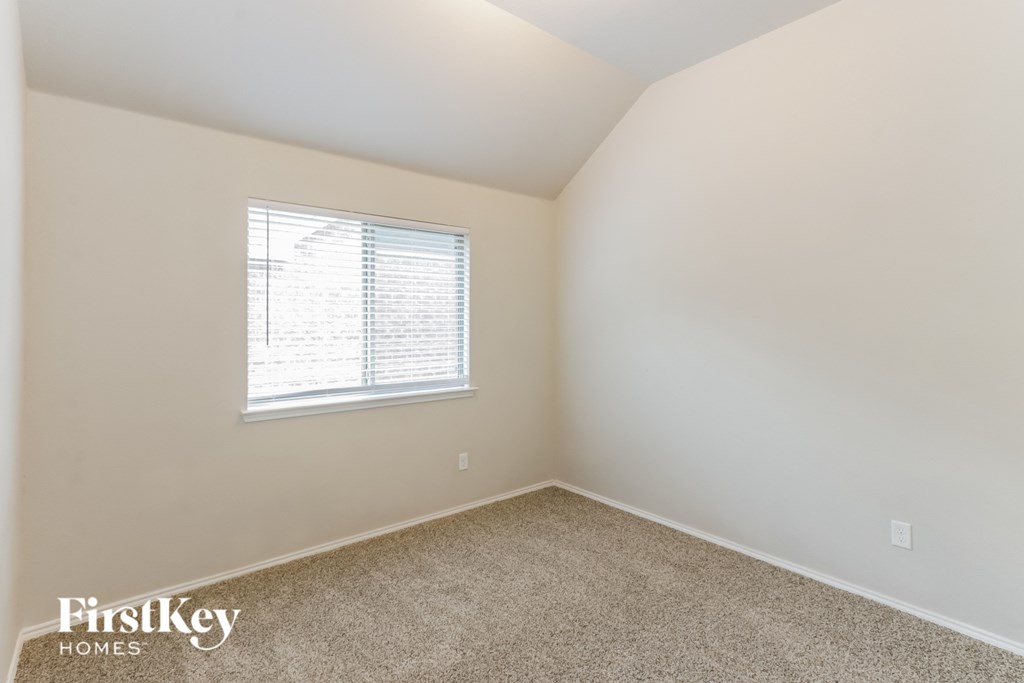A room with a window and a carpeted floor.