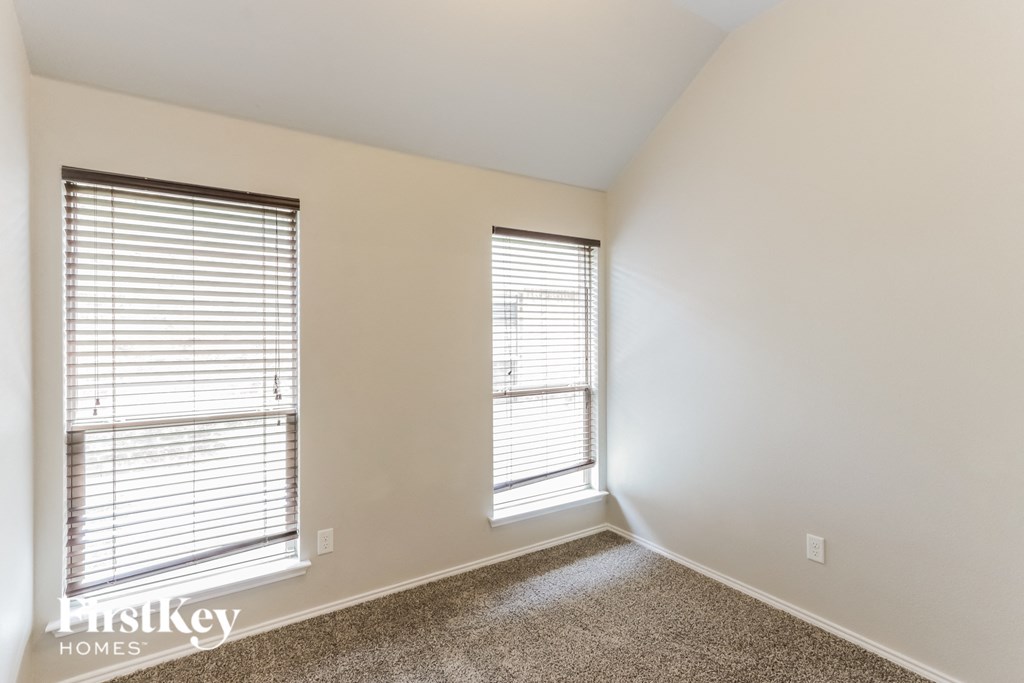 A room with two windows and a carpeted floor.