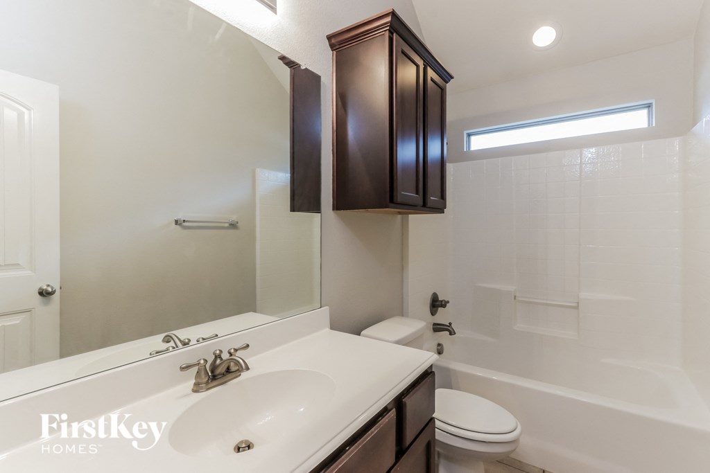 A white sink with a brown cabinet above it.